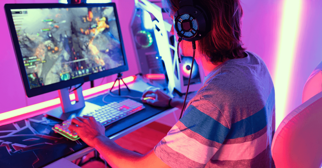 Jovem com headset jogando em um PC com iluminação neon RGB rosa e azul, representando o público de esportes eletrônicos da Brasil Game Show (BGS) em São Paulo.